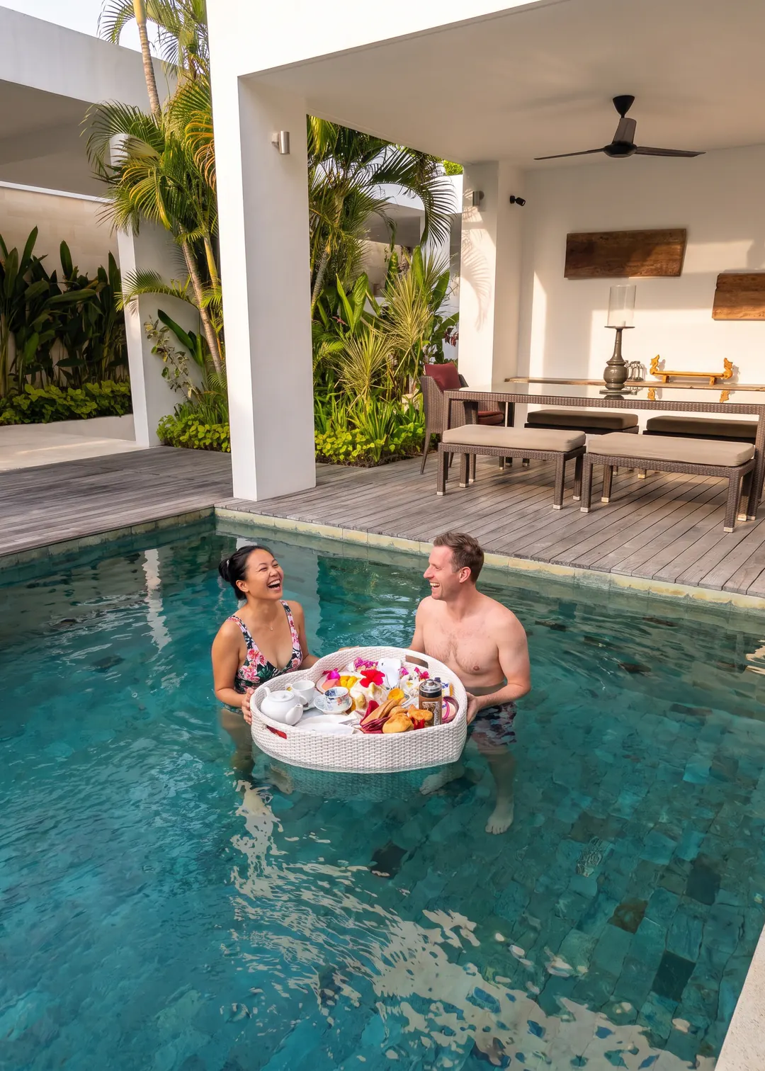A couple in the pool at Casa Brio with the floating breakfast tray between them, laid with pastries, cut fruit, a teapot and frangipani