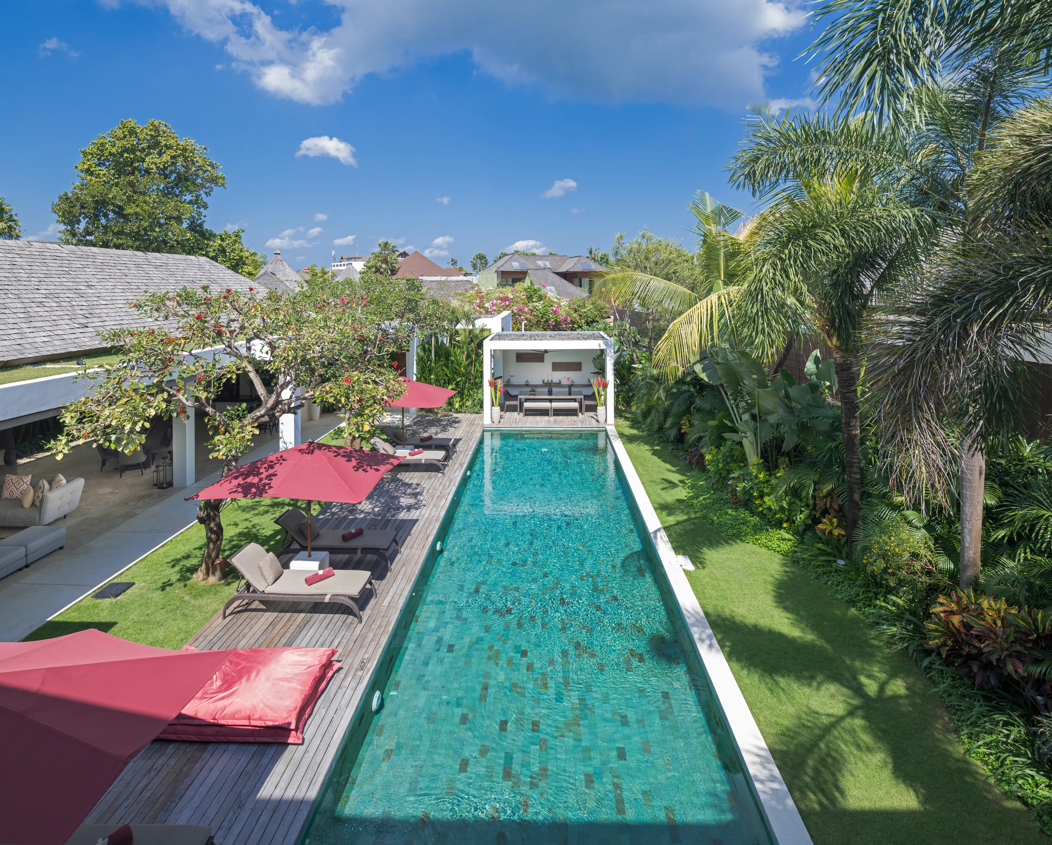 The grounds at Casa Brio from above: the full length of the pool, the deck and loungers under claret parasols, the balé at the far end